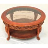 CHERRY CIRCULAR OCCASIONAL TABLE with an inset glass top above a decorative carved frieze,