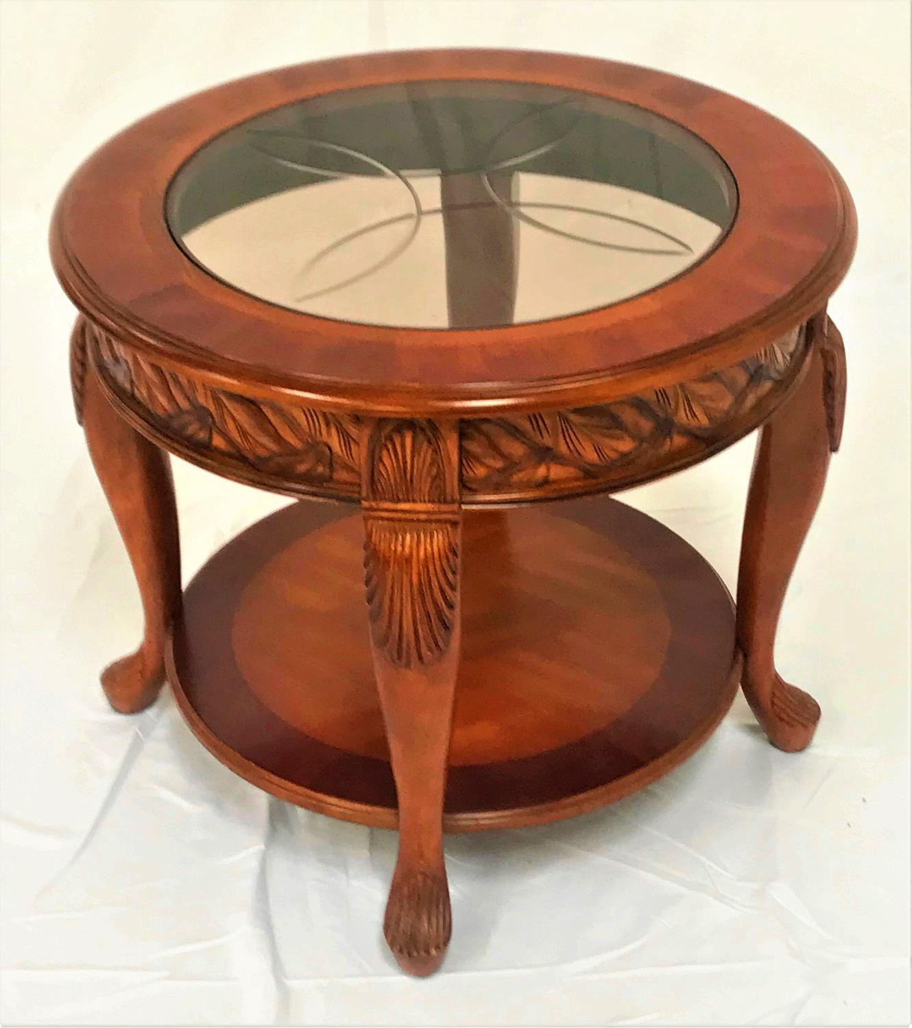 CHERRY CIRCULAR OCCASIONAL TABLE with an inset glass top above a decorative carved frieze,