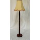 STAINED PINE STANDARD LAMP raised on a circular base with a turned column and shaped cream shade,