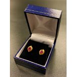 PAIR OF RUBY STUD EARRINGS the oval cut rubies in leaf shaped unmarked gold settings, the