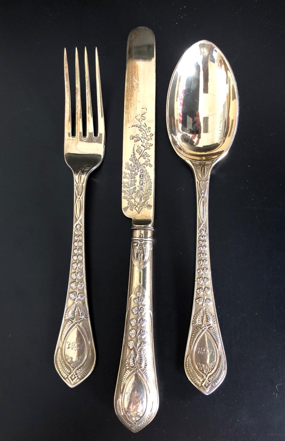 HIGHLY DECORATIVE VICTORIAN SILVER GILT KNIFE, FORK AND SPOON, all with raised foliate decoration to