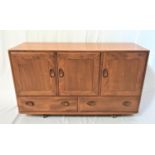 ERCOL LIGHT OAK SIDEBOARD with an oblong top above three panelled cupboard doors, one with a cutlery