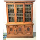 EDWARDIAN OAK BOOKCASE with a moulded pediment above a carved frieze with three leaded glass doors