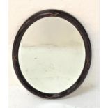 SIMULATED ROSEWOOD WALL MIRROR with an oval frame and bevelled plate, 67.5cm high