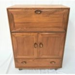 ERCOL LIGHT OAK DRINKS CABINET with an oblong top above a panelled fall flap opening to reveal a