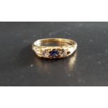 BLUE SAPPHIRE AND CLEAR GEM SET THREE STONE RING the central oval cut blue sapphire flanked by round