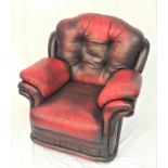 LEATHER ARMCHAIR in red leather with a deep padded back, seat and arms, standing on stout bun feet