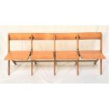 BEECH FOLDING BENCH with four seats below shaped backs, standing on plain supports, 185cm wide