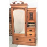 EDWARDIAN SATINWOOD WARDROBE with a shaped and carved pediment above an arched bevelled plate door