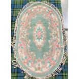 OVAL CHINESE WASH RUG the pale green ground with floral decoration, fringed, 157cm long excluding