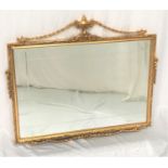 ORNATE GILT FRAME WALL MIRROR with urn and swag decoration around an oblong grooved plate, 92cm wide
