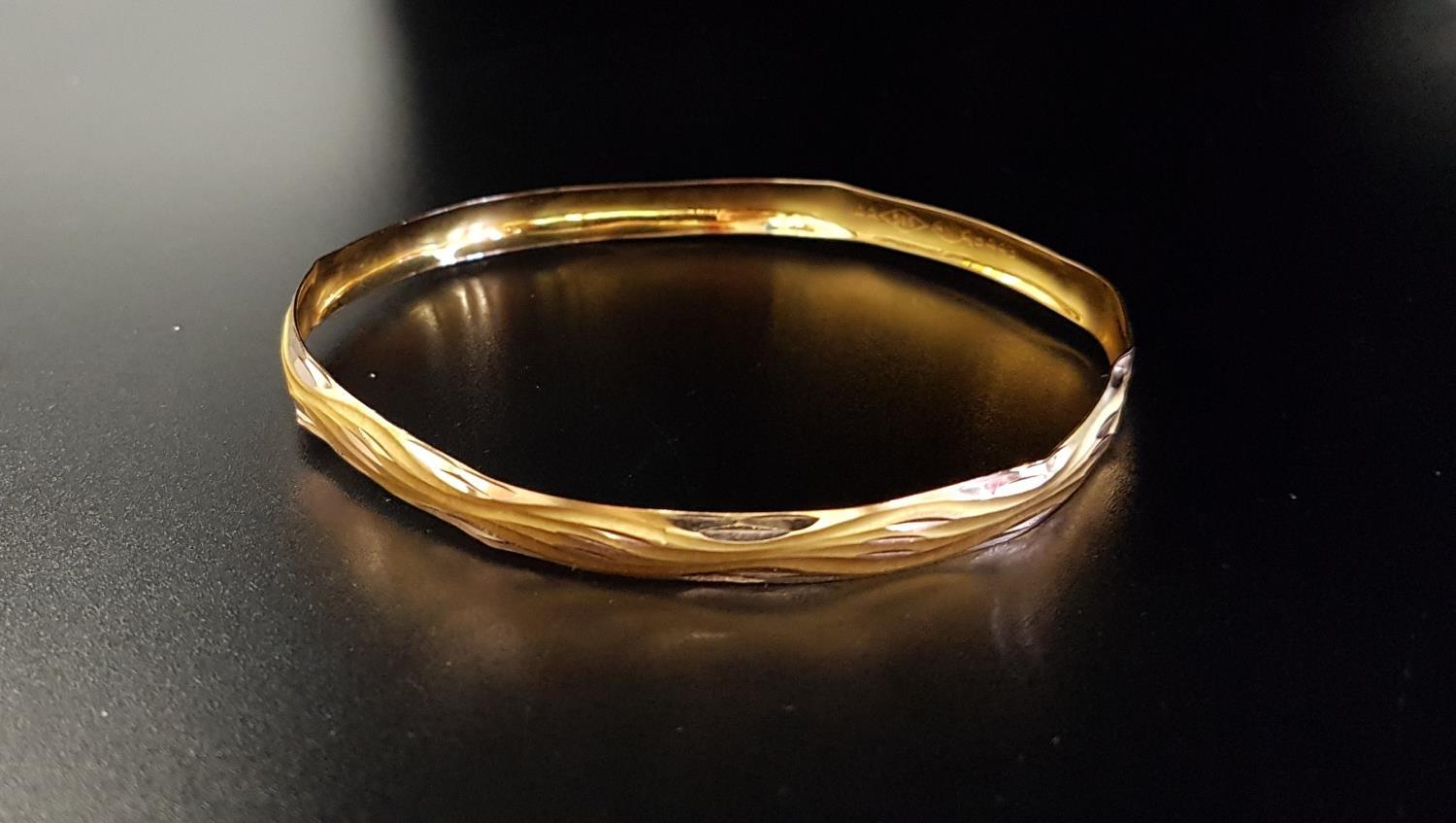 FOURTEEN CARAT GOLD BANGLE with wavy cut decoration, approximately 4.4 grams