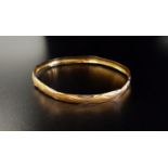 FOURTEEN CARAT GOLD BANGLE with wavy cut decoration, approximately 4.4 grams