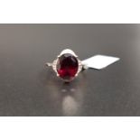 CERTIFIED GARNET AND DIAMOND DRESS RING the central oval cut Rajasthan Garnet surrounded by small
