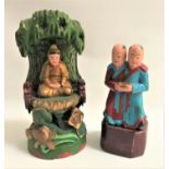 TWO EAST ASIAN POLYCHROME PAINTED CARVINGS one depicting a deity in a grotto with lotus leaf base,
