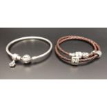 PANDORA MOMENTS SILVER CHARM BANGLE with one flower charm; together with a Pandora Moments double