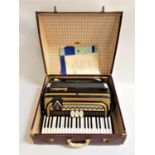 FRONTALINI ACCORDIAN with a black and gold coloured body, shoulder straps and travelling case.