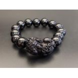 ONYX BEAD BRACELET comprising of thirteen circular beads and one carved dog of foe