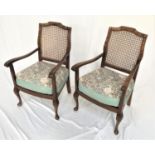 PAIR OF WALNUT BEDROOM CHAIRS with shaped caned backs above shaped arms with stuffover cushion