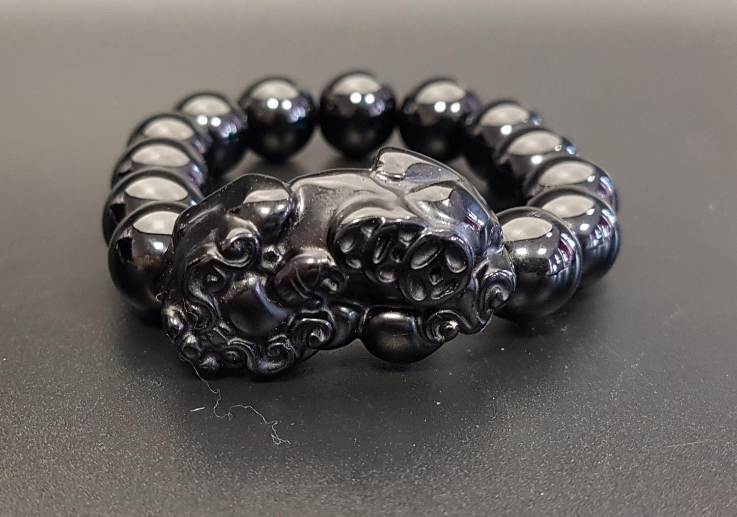 ONYX BEAD BRACELET comprising of thirteen circular beads and one carved dog of foe