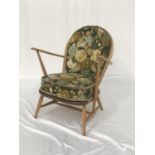 ERCOL BEECH ARM CHAIR with a shaped stick back and arms above a solid seat, with a floral covered