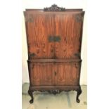 WALNUT ILLUMINATED DRINKS CABINET with a carved and moulded top above a pair of doors with