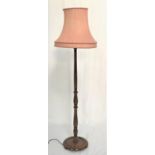 OAK STANDARD LAMP raised on a circular base with a shaped column and coral coloured shaped shade,