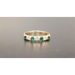 DIAMOND AND EMERALD SEVEN STONE RING set with alternating diamonds and emeralds, the three