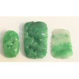 THREE CARVED JADE AMULETS the largest depicting a stylized horse above fruit, 7cm high; another with