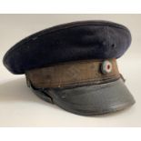 WWII GERMAN NAZI PEAKED CAP in blue cloth with a leather strap, marked to the clear plastic label
