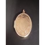 NINE CARAT GOLD LOCKET PENDANT the oval locket with engraved scroll decoration, approximately 3.
