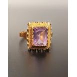 AMETHYST SINGLE STONE RING the emerald cut amethyst in textured and pierced setting, on fourteen