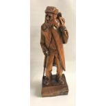 CARVED TEAK FIGURE depicting an old man with a walking stick and bindle over his shoulder,