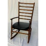 TEAK ROCKING CHAIR with a ladder back and shaped arms above a vinyl padded seat