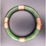 FOURTEEN CARAT GOLD MOUNTED HINGED JADE BANGLE the gold mounts with engraved decoration, with safety