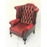 CHESTERFIELD WING BACK ARMCHAIR in red leather with a button back and decorative stud detail,