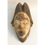 GABON PUNU TRIBAL MASK in carved wood with traces of white applied colour, with carved decoration to