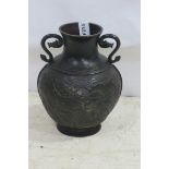 AN ORIENTAL BRONZE VASE of baluster form moulded in relief with dragons and foliage with scroll