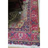 A WOOL RUG the wine ground with central floral panel within a conforming border 393cm x 298cm