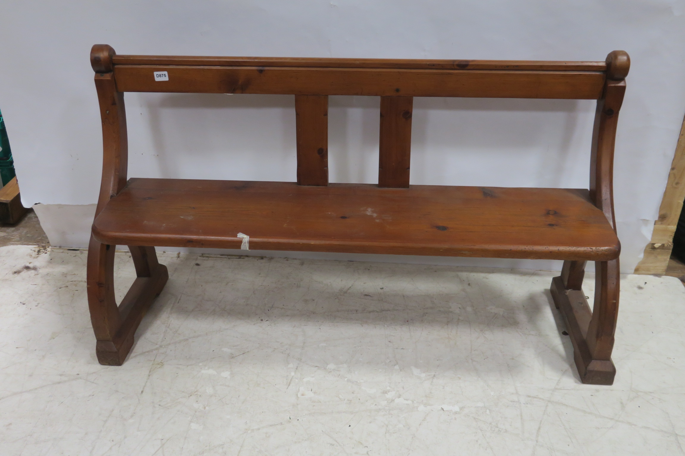 A PINE BENCH the shaped top rail with moulded uprights and panelled seat with curved arm supports