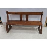 A PINE BENCH the shaped top rail with moulded uprights and panelled seat with curved arm supports