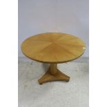 A MAPLE WOOD OCCASIONAL TABLE of circular outline with segmented top above an octagonal column on