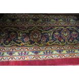 A WOOL RUG the wine and indigo ground with central floral panel within a conforming border 397cm x