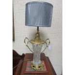 A PAIR OF GILT BRASS AND CUT GLASS TABLE LAMPS with pierced scroll handles raised on a rococo base