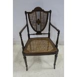 A 19TH CENTURY MAHOGANY POLYCHROME AND BERGERE ELBOW CHAIR the shield shape caned back and seat on