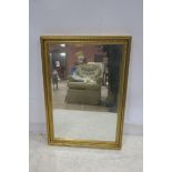 A GILT FRAMED MIRROR the rectangular bevelled plate within a fluted frame 64cm x 97cm