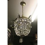 A CONTINENTAL GILT BRASS AND CUT GLASS BASKET CENTRE LIGHT hung with faceted pendants