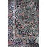 A WOOL RUG the light green ground with central floral panel within a conforming border 197cm x