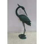 A GREEN PATINATED METAL FIGURE modelled as a heron shown standing on a naturalistic base 142cm x