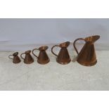 A SET OF FIVE COPPER GRADUATED SPIRIT MEASURES together with brass ladle and spoon